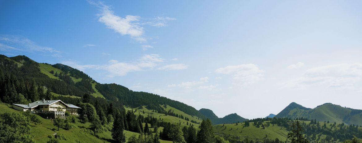 Das Foto zeigt die Jugendherberge Sudelfeld in der Totalen auf einem grünen bewaldeten Hang.